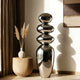 Mirror Polished Balancing Stone Stainless Steel Sculpture  in a room with a vase and pampas grass.