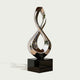 Gleaming Infinity Abstract Stainless Steel Sculpture on a glossy black rectangular base, set against a light gray background.