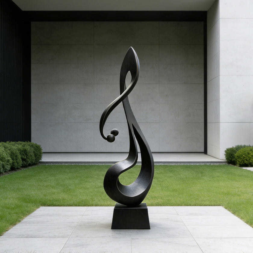 Lyrical Musical Note Black Stainless Steel Sculpture on a rectangular black base, set outdoors on a light stone patio with green grass and a minimalist concrete building in the background.