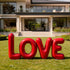 Balloon Style Red LOVE Custom Stainless Steel Sculpture on a green lawn in front of a modern house.
