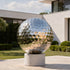 Mirror Polished Golf Ball Contemporary Stainless Steel Sculptures sits on a round concrete pedestal in a modern outdoor garden setting.
