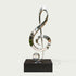 Modern Musical Note Outdoor Stainless Steel Sculpture on a rectangular black base, photographed against a plain light warm-gray background.