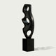 Abstract Large Voids Stainless Steel Sculpture with three circular cutouts, mounted on a rectangular black pedestal, set against a light gray background.