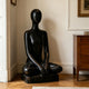 Peaceful Meditating Seated Figure Stainless Steel Indoor Sculpture on a wooden floor in a styled interior room with cream walls and a wood cabinet.