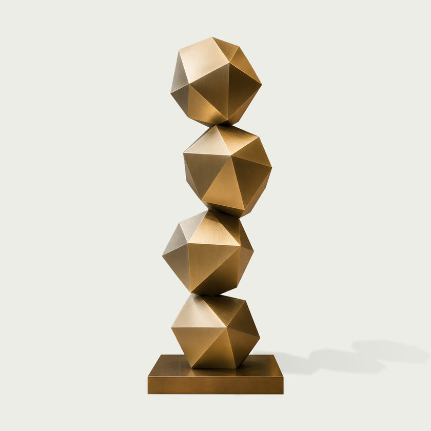 Stacked Geometric Polyhedron Abstract Stainless Steel Sculpture featuring four stacked faceted geometric spheres in a metallic gold finish, resting on a matching rectangular base against a light gray background.