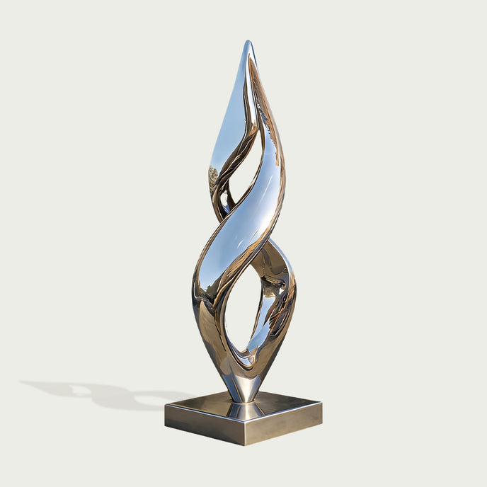 A modern abstract metallic sculpture with a reflective silver finish, mounted on a square base against a light gray background.