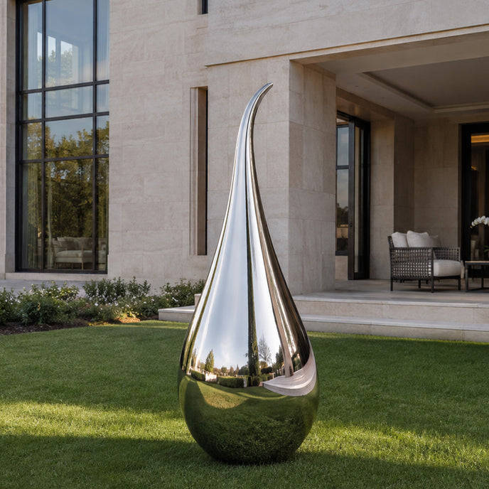Side-Hook Curved Water Drop Mirror Polished Stainless Steel Sculpture on a lawn in front of a modern villa