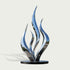 A modern abstract flame-shaped sculpture made of highly polished reflective metal, mounted on a round black base against a light gray background.