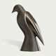 A modern metallic bird sculpture with a perforated honeycomb pattern on its body and a smooth, reflective wing, displayed on a light off-white background.