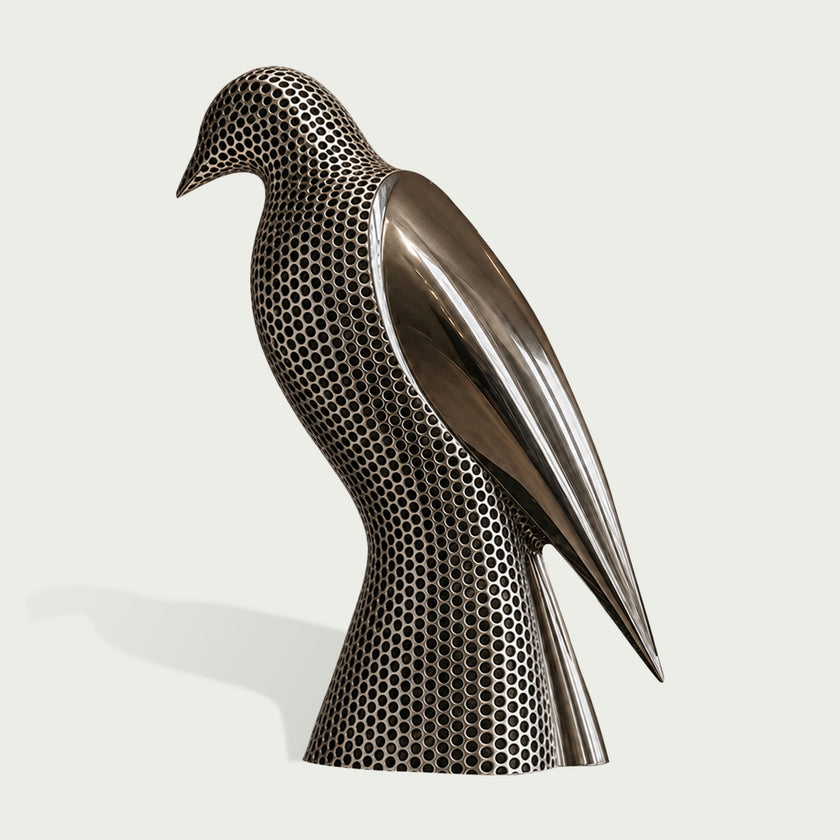 A modern metallic bird sculpture with a perforated honeycomb pattern on its body and a smooth, reflective wing, displayed on a light off-white background.