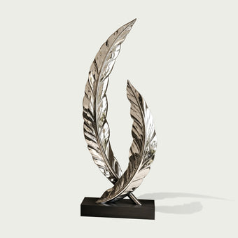 A mirror-polished stainless steel sculpture of two intersecting curved feathers on a black base on a white background