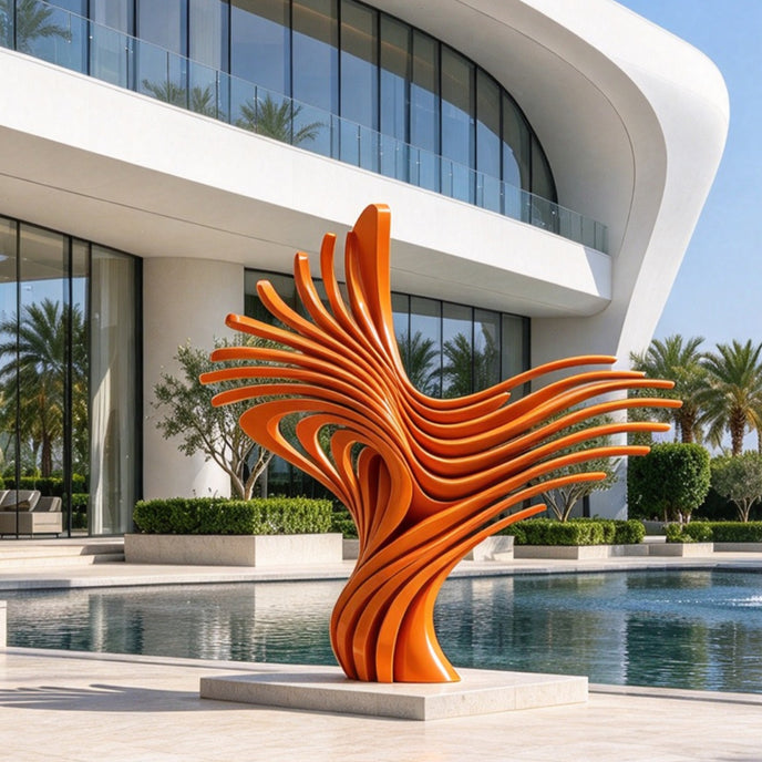 Large contemporary abstract stainless steel sculpture featuring a vibrant orange finish, displayed beside a swimming pool in the courtyard of a luxury modern villa. The sculpture consists of numerous elongated, curved metal ribbons that rise from a narrow central base and fan outward in multiple directions, creating a dramatic flowing composition reminiscent of spreading wings, flames, or organic waves. Its smooth, glossy orange surfaces emphasize the layered structure, graceful sweeping curves, and open sp