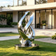 Modern polished stainless steel ribbon sculpture installed in a luxury garden, featuring flowing curved loops and a mirror reflective surface. The contemporary outdoor artwork enhances modern architecture with its elegant abstract form.