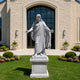 Large white granite Jesus Christ statue with open arms displayed in front of a church entrance, showcasing detailed robe folds and sacred architectural decor