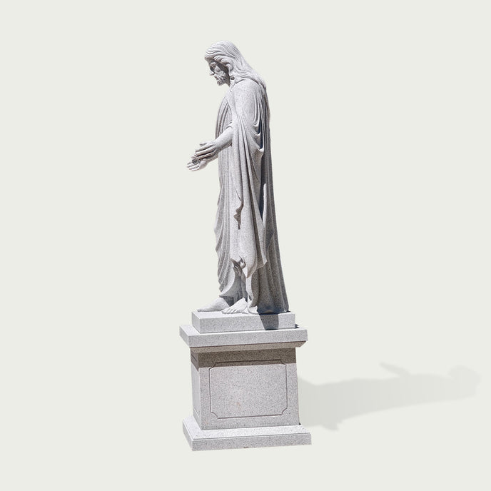 Side view of carved granite Jesus Christ statue showing realistic robe textures, long hair details, and traditional Christian sculpture craftsmanship