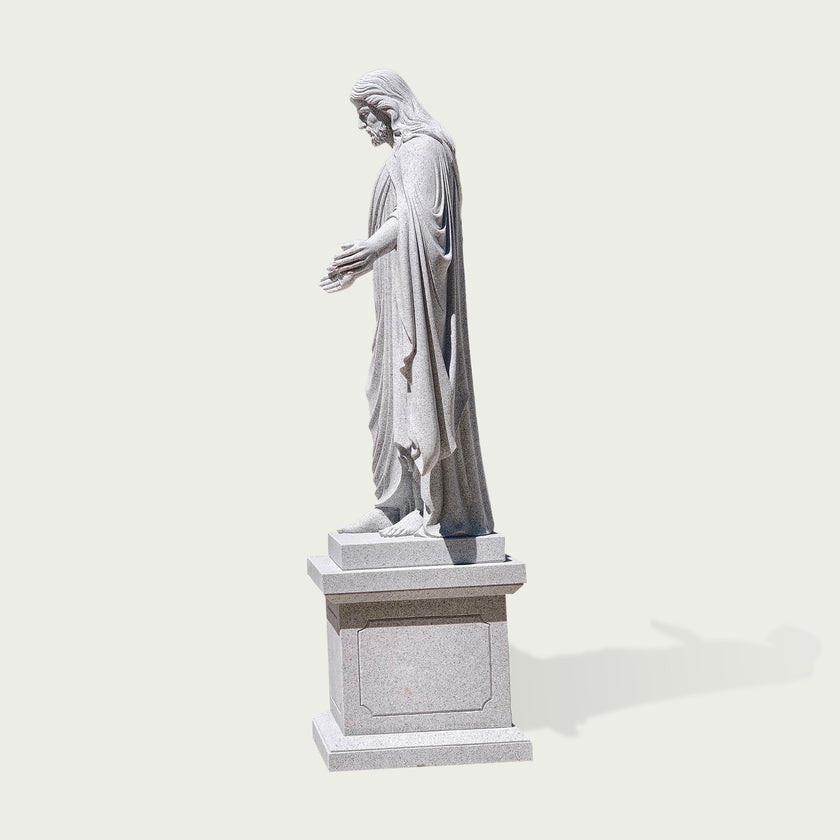 Side view of carved granite Jesus Christ statue showing realistic robe textures, long hair details, and traditional Christian sculpture craftsmanship